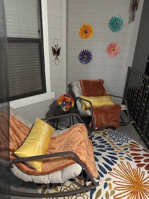 Una habitació acollidora amb dues cadires bressol, un moqueta estampada i flors decoratives a la paret.