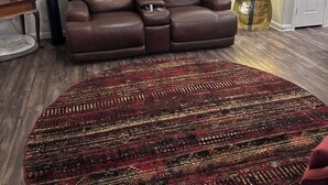 A brown leather sofa with a footrest, a round patterned rug, a decorative wall piece, and a floor lamp. - Cozy 1-bedroom apartment with AC in lovely Frisco (Frisco)