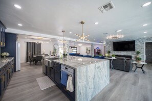Een moderne keuken met een marmeren eiland, inbouwapparatuur en hanglampen.