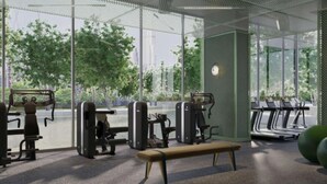 Una palestra moderna con attrezzature per esercizi, una panca e ampie finestre con vista su alberi e edifici.