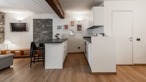 Una cocina compacta con una isla central, estufa integrada y un televisor de pantalla plana montado en la pared.