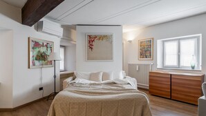 Un dormitorio con cama, cómoda, radiador y obras de arte en las paredes.