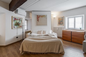 Ein Schlafzimmer mit einem Bett, einem Schminktisch, einem Heizkörper und Bildern an den Wänden.