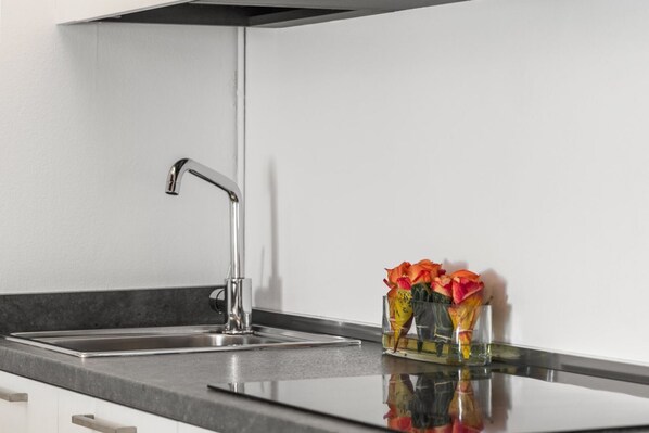 Eine moderne Küche mit Armatur aus Edelstahl, einer Arbeitsfläche und einer Vase mit Blumen.