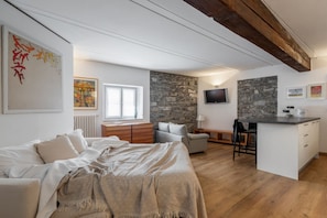 Ein modernes Schlafzimmer mit einem großen Bett, einer Steinwand, einem Fernseher und einer Küchenzeile.