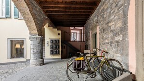 Una escalera de piedra que lleva a un nivel superior, una bicicleta apoyada en una pared y un pilar de piedra.