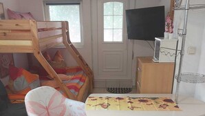 Una habitación con una cama litera, un escritorio con silla, un televisor y una alfombra estampada.