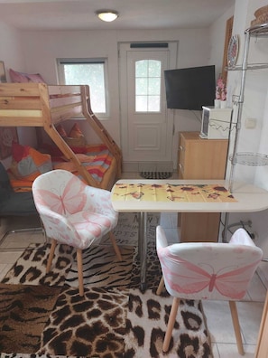 A room with a bunk bed, a desk with a chair, a television, and a patterned rug. - Vacation apartment Zwergenstübchen (Lübstorf)