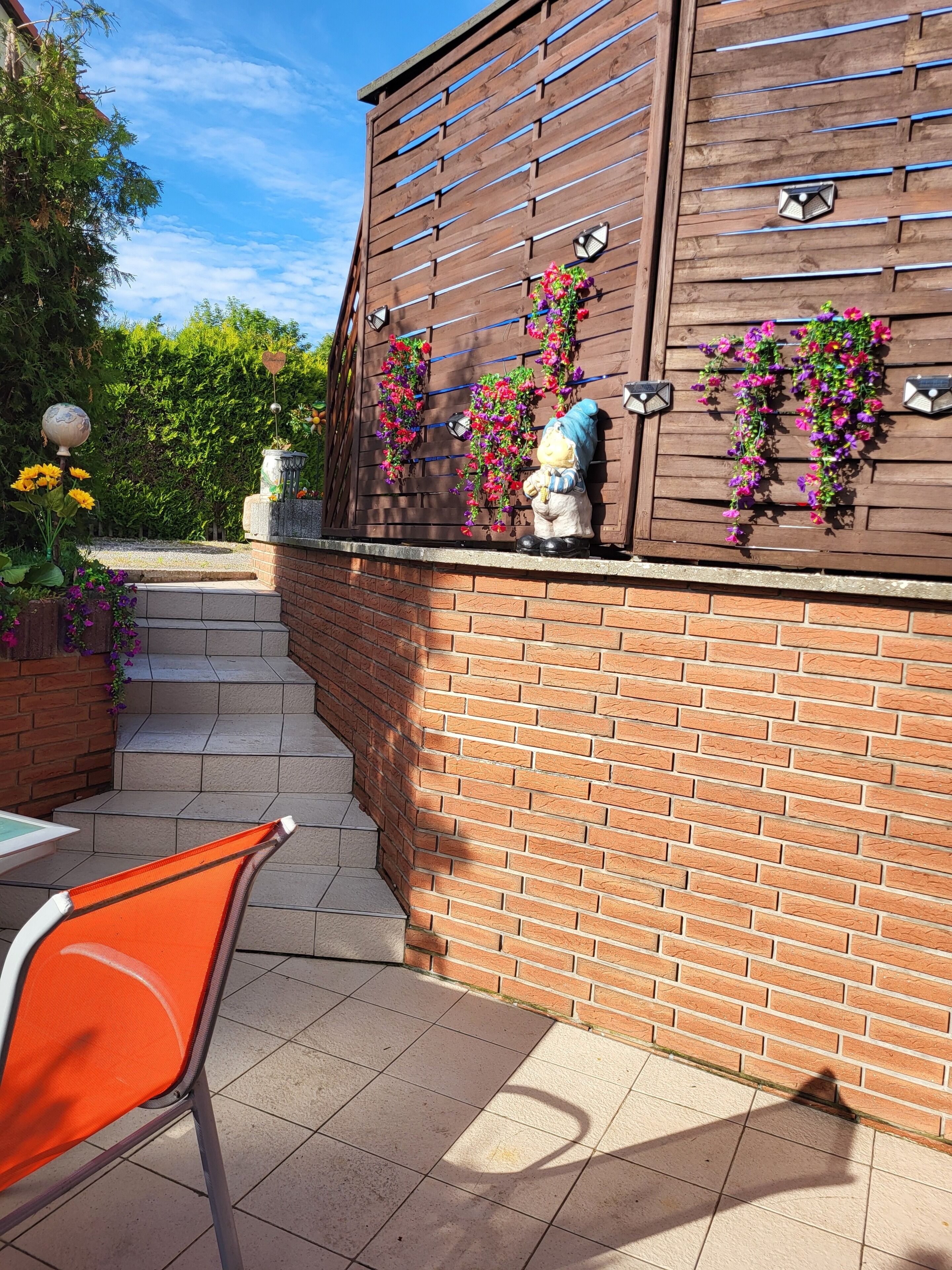 A brick wall with a wooden fence, a statue, and a chair.
