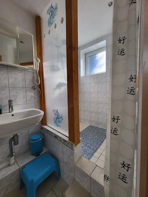 A bathroom with a sink, mirror, shower curtain, and a small stool.