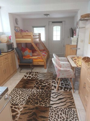 A child's bunk bed with a desk and chair, a microwave, and a patterned rug in a small room. - Vacation apartment Zwergenstübchen (Lübstorf)