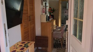 Una sala de estar con televisión, muebles de madera, una estantería y una puerta que da a otra habitación.