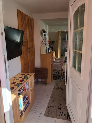 A living room with a television, wooden furniture, a bookshelf, and a door leading to another room. - Vacation apartment Zwergenstübchen (Lübstorf)