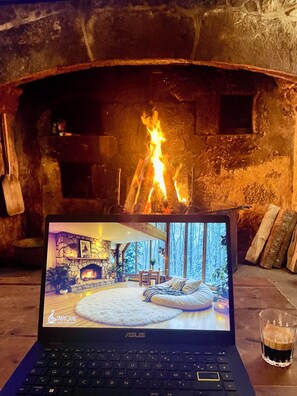 Una computadora portátil que muestra una habitación con chimenea, una cama y un vaso de bebida.