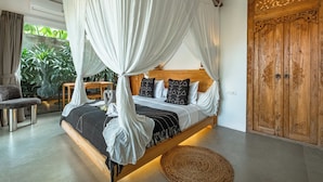 Quarto com cama de dossel, guarda-roupa de madeira e vista para o verde lá fora.