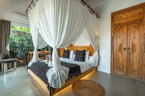 Ein Schlafzimmer mit Baldachinbett, Holzschrank und Blick ins Grüne.