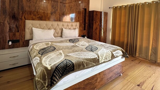 A modern bedroom with a wooden headboard, a bed with a patterned bedspread, a ceiling fan, and a view of the outside through a window.