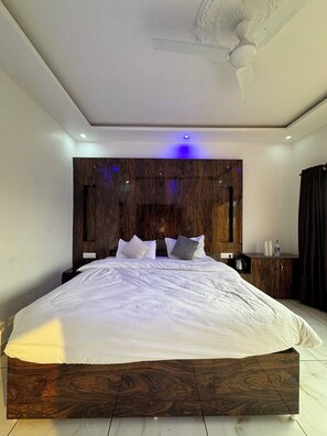 Quarto moderno com cama grande, cabeceira de madeira e ventilador de teto.