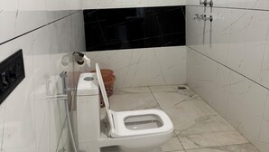 A modern bathroom with a toilet, shower, and sink.