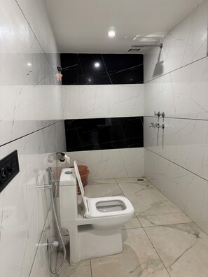 Uma casa de banho moderna com sanita, chuveiro e lavatório.