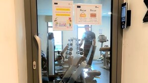 Una palestra con attrezzature per esercizi, una porta in vetro e un display digitale.