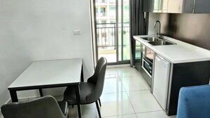 Una cucina compatta con zona pranzo, un divano blu e vista attraverso una porta vetrata.
