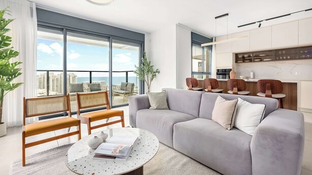 Ein modernes Wohnzimmer mit einem grauen Sofa, Holzstühlen, einem runden Couchtisch und einem großen Fenster mit Blick auf die Stadt.