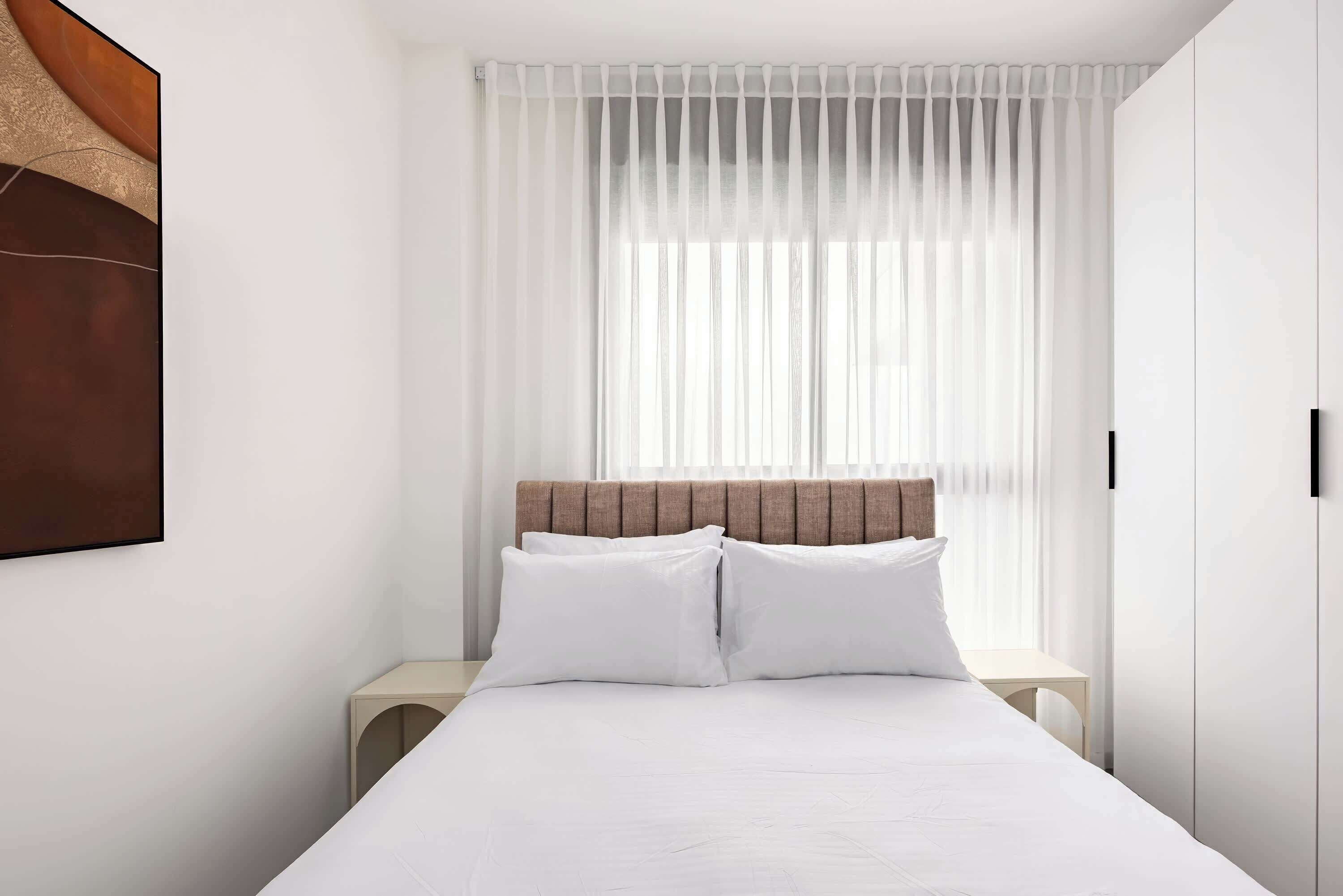 A neatly arranged bedroom with a bed, bedside tables, and a headboard.