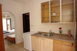 Eine kleine Küche mit Kühlschrank, Spüle und einem Schrank mit Glastüren.