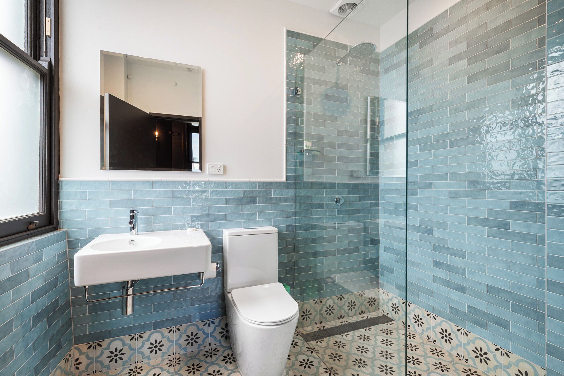 Een badkamer met een wit wastafelmeubel, een toilet en een douchecabine van glas.