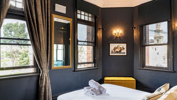 A hotel room with a large bed, a bench, a framed picture, and a window with a view of a building. - Imperial Hotel Paddington (Paddington)