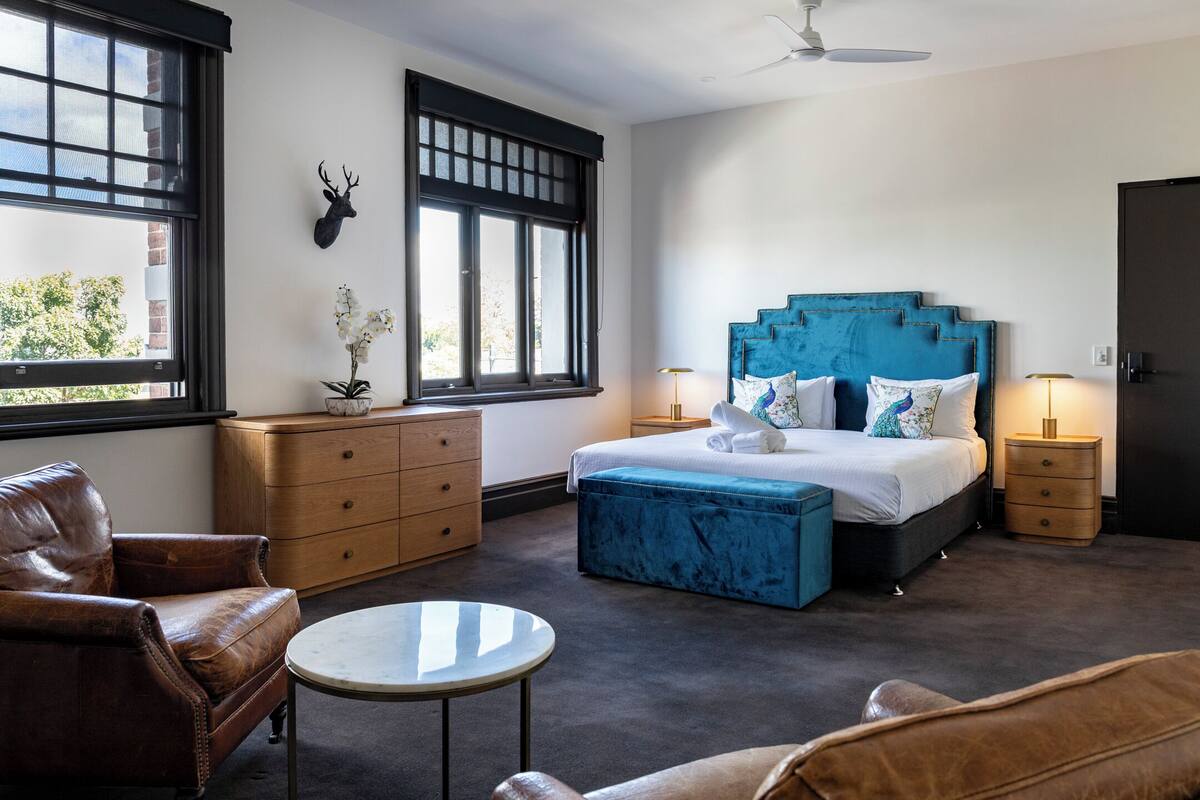 A bedroom with a bed, a dresser, a chair, a round table, and a window with a view.