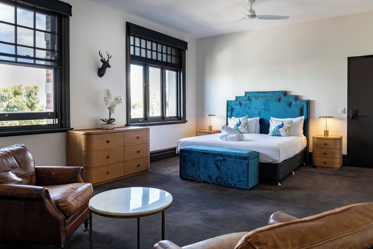 A bedroom with a bed, a dresser, a chair, a round table, and a window with a view.