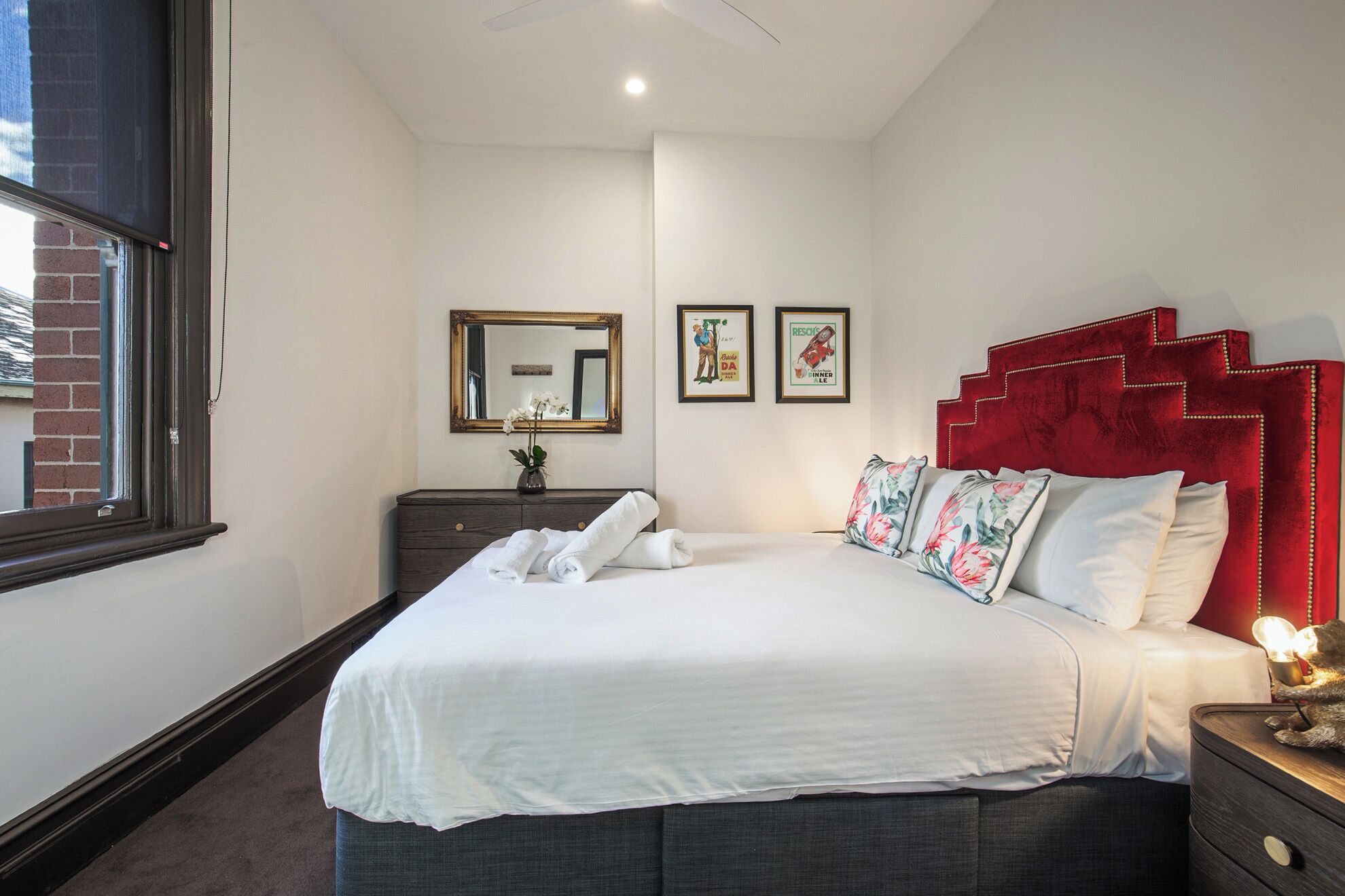 Habitación de hotel con una cama, un tocador, un espejo y dos cuadros en la pared.