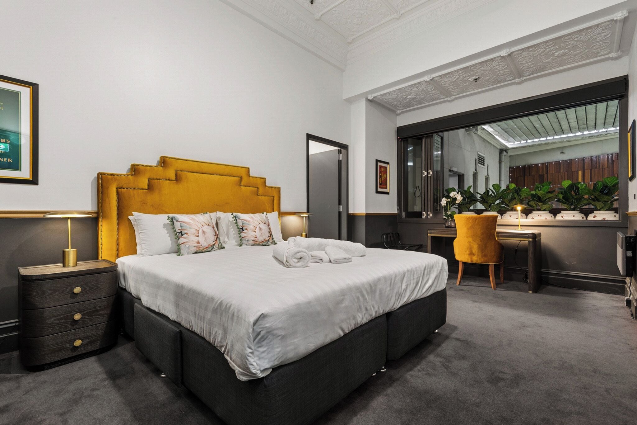 Un dormitorio moderno con una cama grande, mesitas de noche, un escritorio y una silla.