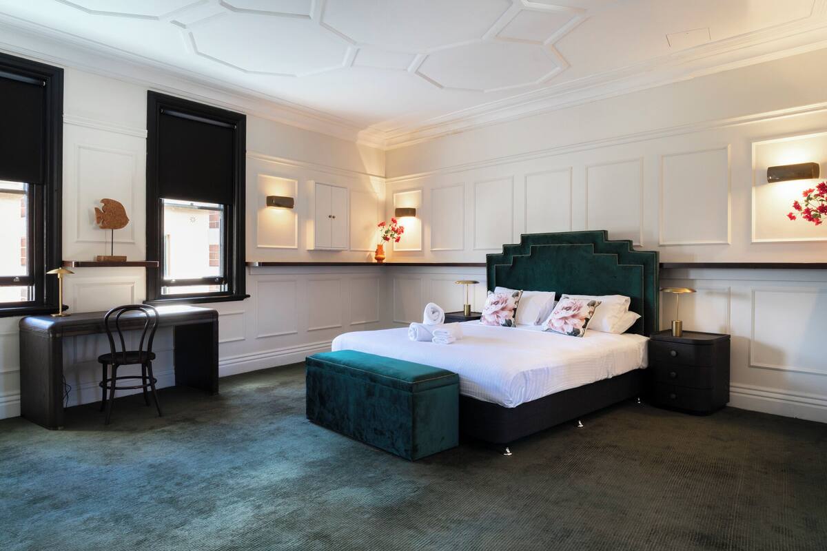 A bedroom with a large bed, a desk, and a chair.