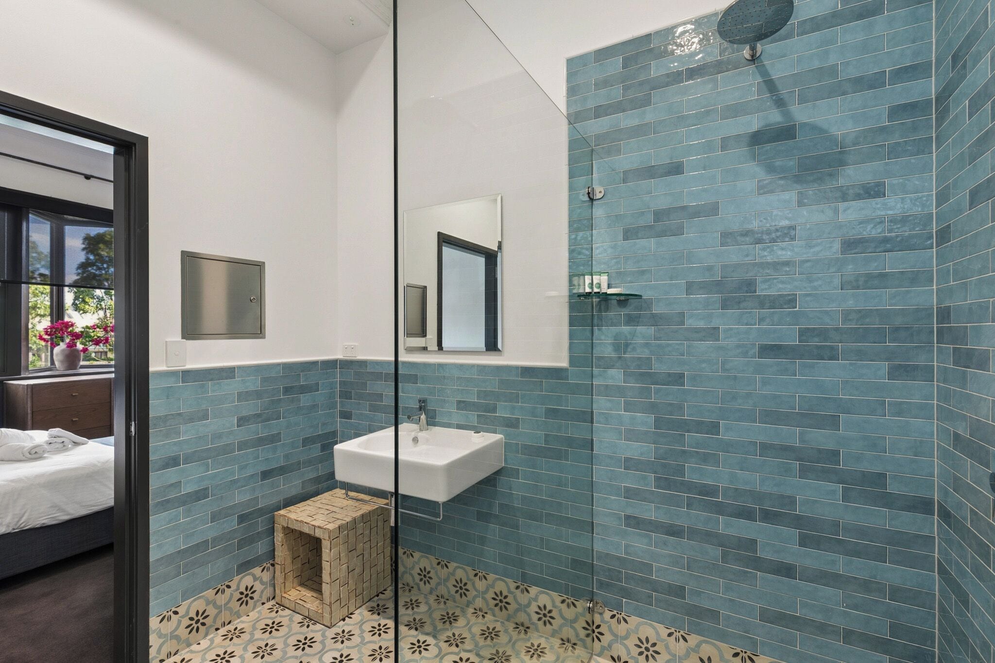 Un bagno moderno con doccia, lavandino e un piccolo sgabello di legno.