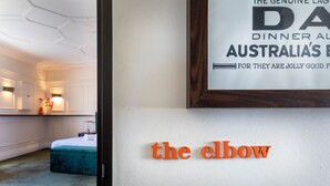 A framed sign with text, a bed, and a wall with a partial text 'the elbow'. - Imperial Hotel Paddington (Paddington)