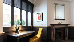 A room with a desk, a yellow chair, a fireplace, and a large mirror on the wall. - Imperial Hotel Paddington (Paddington)