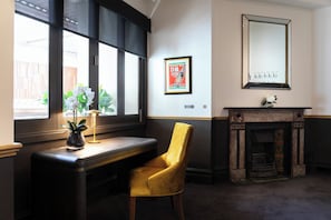 A room with a desk, a yellow chair, a fireplace, and a large mirror on the wall. - Imperial Hotel Paddington (Paddington)