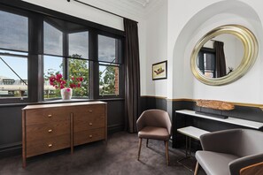 A room with a large window, a wooden dresser, two chairs, a desk, and a round mirror. - Imperial Hotel Paddington (Paddington)