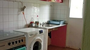 Een keuken met een wasmachine, een spoelbak en een raam.