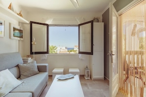 A room with a sofa, a table, a cabinet, and a window with an open door. - Apartment with pool dofins 6 (Ciutadella)