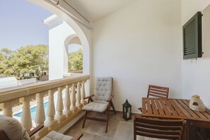 Ein Balkon mit Pool, einem Holztisch, einem gepolsterten Stuhl und einer kleinen Laterne.
