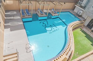 Ein Pool auf dem Dach mit Liegestühlen, einem Schild mit der Nummer 37 und dem Schriftzug 'KIK AMBALA'.