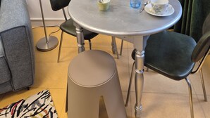 Ein Essbereich mit einem runden Tisch, Stühlen, einem gerahmten Kunstwerk an der Wand, einer Wasserflasche und einer Tasse auf dem Tisch.