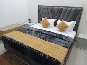 Un lit bien fait, avec une couvre-lit à motifs, deux oreillers et une table de chevet sur laquelle se trouve une lampe.