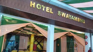 L'ingresso di un hotel con un cartello che riporta 'HOTEL SWAYAMBHU', coperto da drappeggi.
