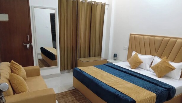 Una camera d'albergo con un letto, un divano, uno specchio e una finestra con tende.
