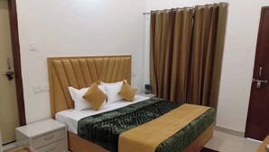 Una camera da letto con un letto, un comodino, un cassetto, una finestra con tende e una porta.